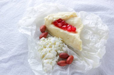 Camembert ve süzme peynir beyaz kumaş üzerine. Çeşitli peynir, fıstık ve beyaz arka plan üzerinde tatlım. Peynir, nar taneleri ve fındık. Sağlıklı gıda