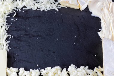 Peynir siyah arka plan üzerine çeşitli türü. Farklı peynir yaratıcı kopya alanı ile siyah arduvaz gemide. Bir çerçeve üst şeklinde süt ürünleri göster