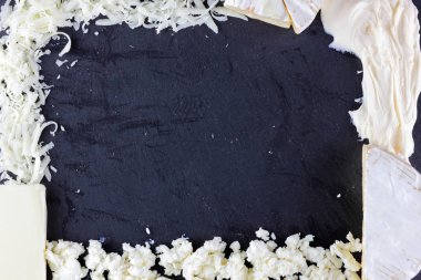 Peynir siyah arka plan üzerine çeşitli türü. Farklı peynir yaratıcı kopya alanı ile siyah arduvaz gemide. Bir çerçeve üst şeklinde süt ürünleri göster