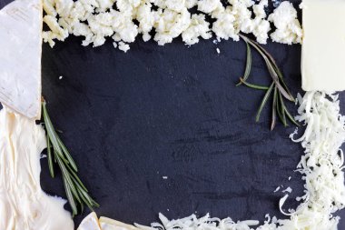 Peynir ve siyah arka plan üzerine biberiye çeşitli türü. Farklı peynir yaratıcı kopya alanı ile siyah arduvaz gemide. Bir çerçeve üst şeklinde süt ürünleri göster