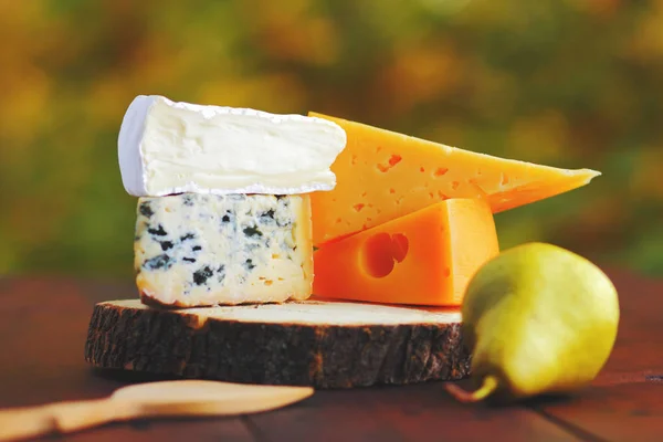 木板上有各种类型的奶酪和梨 在模糊的背景上的奶酪片 多布卢 卡门伯特和硬黄色奶酪 — 图库照片