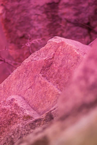 Granite rock in pink tinting. Granite close up. Texture of stone with coral color. Background from natural material with red shades