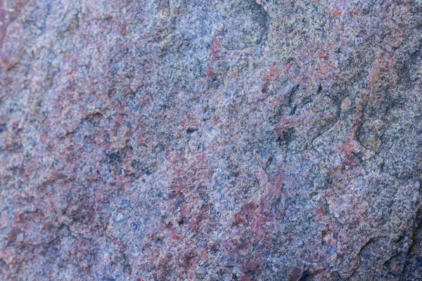 Texture of granite close up. Granite rock with reddish color. Background from solid stone. Pattern with natural material