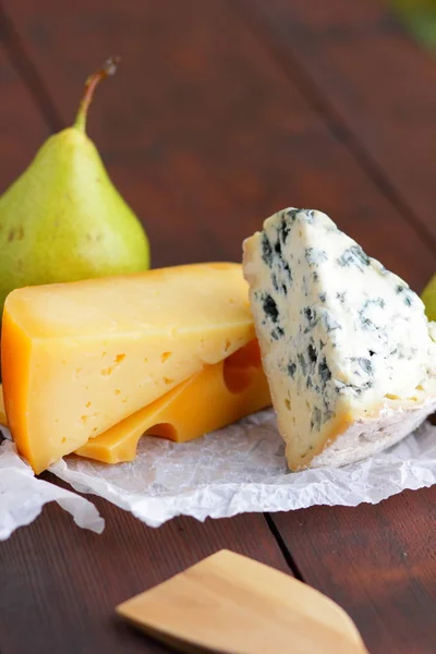 木板上的奶酪和梨 各种奶酪在自然模糊的背景 羊皮纸上的多布布 卡门伯特和硬黄色奶酪 — 图库照片