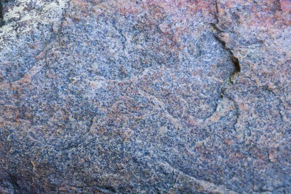 Texture of granite close up. Granite rock with reddish color. Background from solid stone. Pattern with natural material