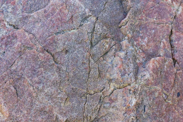 Texture of granite close up. Granite rock with reddish color. Background from solid stone. Pattern with natural material