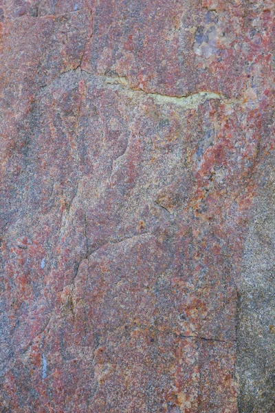 Texture of granite close up. Granite rock with reddish color. Background from solid stone. Pattern with natural material