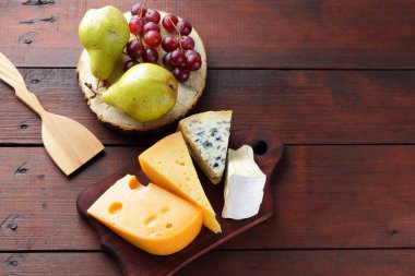 Peynir, armut ve ahşap kurullarında üzüm türleri. Peynir ve meyve ahşap arka plan üzerinde. Dorblu, camembert ve sert sarı peynir. Üstten Görünüm