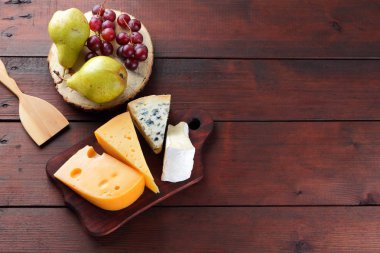 Peynir, armut ve ahşap kurullarında üzüm türleri. Peynir ve meyve ahşap arka plan üzerinde. Dorblu, camembert ve sert sarı peynir. Üstten Görünüm