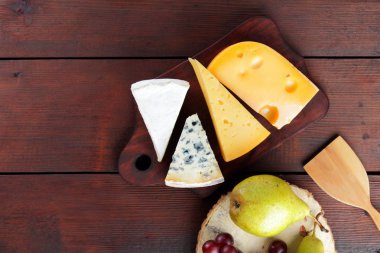 Peynir, armut ve ahşap kurullarında üzüm türleri. Peynir ve meyve ahşap arka plan üzerinde. Dorblu, camembert ve sert sarı peynir. Üstten Görünüm