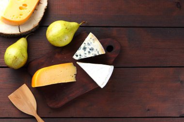 Peynir ve armut ahşap kurullarında çeşitli türleri. Peynir ve meyve ahşap arka plan üzerinde. Dorblu, camembert ve sert sarı peynir. Üstten Görünüm