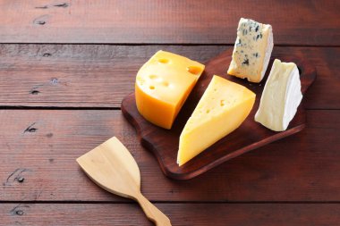Peynir ahşap kurullarında. Ahşap arka plan üzerinde peynir türleri. Dorblu, camembert ve sert sarı peynir. Üstten Görünüm
