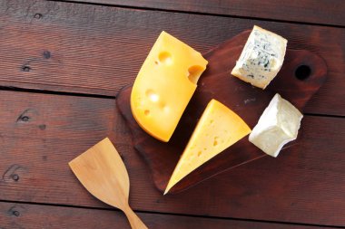 Peynir ahşap kurullarında. Ahşap arka plan üzerinde peynir türleri. Dorblu, camembert ve sert sarı peynir. Üstten Görünüm