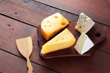 Peynir ahşap kurullarında. Ahşap arka plan üzerinde peynir türleri. Dorblu, camembert ve sert sarı peynir. Üstten Görünüm