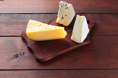 Peynir ahşap kurullarında. Ahşap arka plan üzerinde peynir türleri. Dorblu, camembert ve sert sarı peynir. Üstten Görünüm