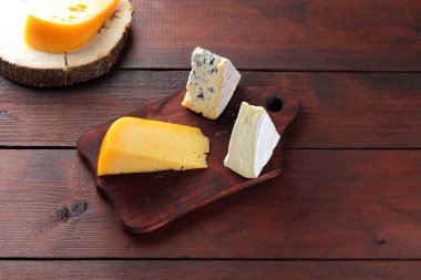 Peynir ahşap kurullarında. Ahşap arka plan üzerinde peynir türleri. Dorblu, camembert ve sert sarı peynir. Üstten Görünüm