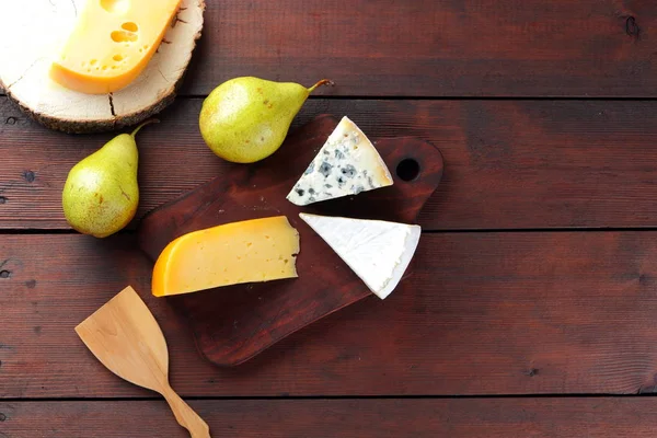 Peynir ve armut ahşap kurullarında çeşitli türleri. Peynir ve meyve ahşap arka plan üzerinde. Dorblu, camembert ve sert sarı peynir. Üstten Görünüm