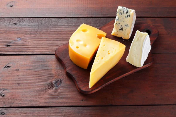 Peynir ahşap kurullarında. Ahşap arka plan üzerinde peynir türleri. Dorblu, camembert ve sert sarı peynir. Üstten Görünüm