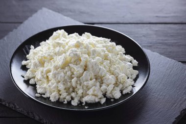 Süzme peynir siyah arduvaz gemide. Siyah plaka üzerinde süzme peynir. Yumuşak peynir diyet siyah panoları için. Kahvaltı için sağlıklı süt ürünleri. Kavramı