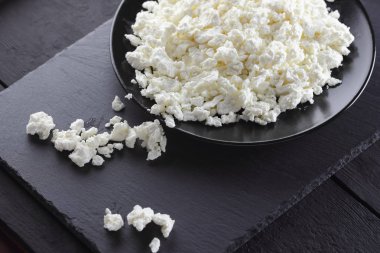 Süzme peynir siyah arduvaz gemide. Siyah plaka üzerinde süzme peynir. Yumuşak peynir diyet siyah panoları için. Kahvaltı için sağlıklı süt ürünleri. Kavramı