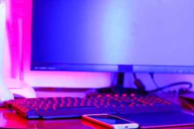 İşyeri dijital Tasarımcısı. Freelancer işyerinde neon ışık. Bilgisayar, grafik tablet ve smartphone masanın üzerinde. Mavi-pembe ışık yaratıcılık için yer