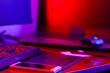 İşyeri dijital Tasarımcısı. Freelancer işyerinde neon ışık. Bilgisayar, grafik tablet ve smartphone masanın üzerinde. Mavi-pembe ışık yaratıcılık için yer