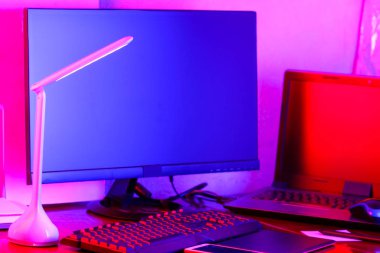 İşyeri dijital Tasarımcısı. Freelancer işyerinde neon ışık. Bilgisayar, grafik tablet ve smartphone masanın üzerinde. Mavi-pembe ışık yaratıcılık için yer