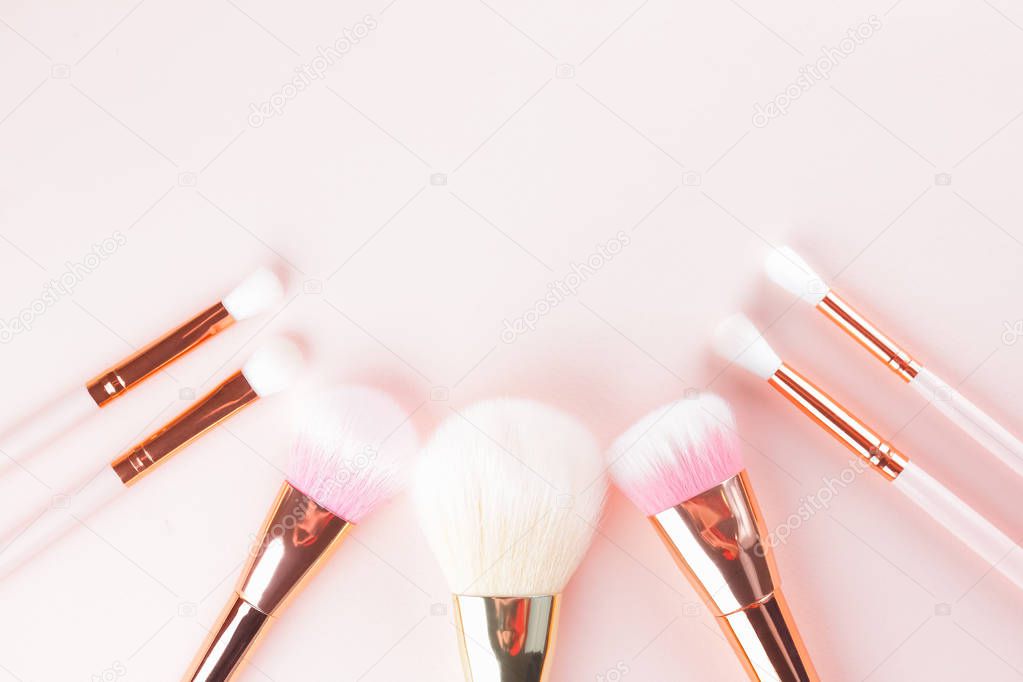 Makeup brushes on pink background. Set of golden makeup brushes, concept. Woman beauty accessory in pastel colors. Copy space. Flat lay
