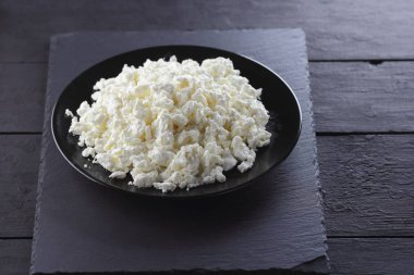 Süzme peynir siyah arduvaz gemide. Peynir siyah plaka üzerinde. Yumuşak peynir diyet siyah panoları için. Kahvaltı için sağlıklı süt ürünleri. Kavramı