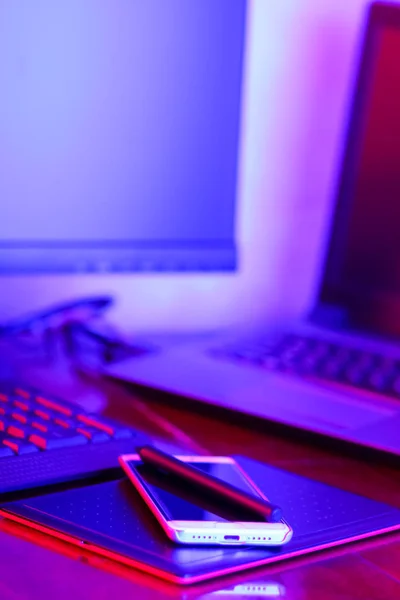 職場デジタル デザイナー ネオンの光でフリーランサー職場 コンピューター グラフィックス タブレット スマート フォン テーブルの上 青ピンクの光の創造のための場所 — ストック写真