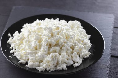 Süzme peynir siyah arduvaz gemide. Peynir siyah plaka üzerinde. Yumuşak peynir diyet siyah panoları için. Kahvaltı için sağlıklı süt ürünleri. Kavramı