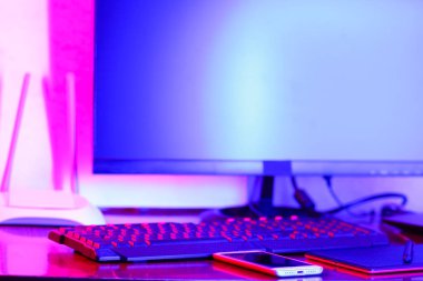 İşyeri dijital Tasarımcısı. Freelancer işyerinde neon ışık. Bilgisayar, grafik tablet ve smartphone masanın üzerinde. Mavi pembe ışık yaratıcılık için yer