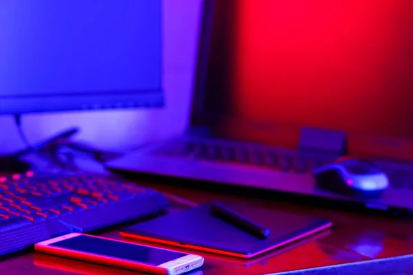 職場デジタル デザイナー ネオンの光でフリーランサー職場 コンピューター グラフィックス タブレット スマート フォン テーブルの上 青ピンクの光の創造のための場所 — ストック写真