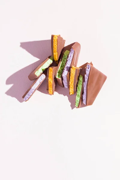 Chocolate with fruit filling on pink background. Slices of chocolate with blueberries, mint and orange. Dark chocolate on pastel color background. Concept