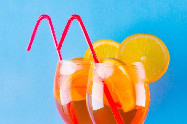 Kokteyl aperol spritz mavi zemin üzerine. Yaz alkollü kokteyl ile portakal dilimleri. Aperol spritz renkli arka plan üzerinde. Minimalizm tarzı kokteyl renkli mercan