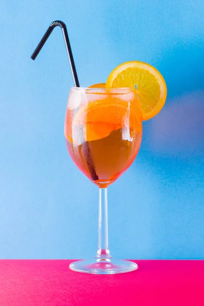 鸡尾酒杯在红色蓝色背景上的冲刺 夏季酒精鸡尾酒 配橘子片 在彩色背景上的阿佩罗斯普里茨 简约风格的珊瑚色鸡尾酒 — 图库照片