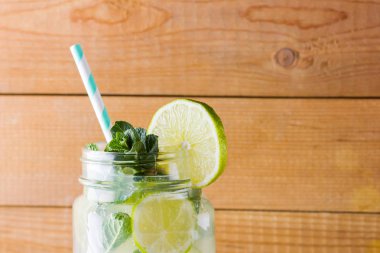 Mojito ve ahşap zemin üzerine nane. Kireç ve ahşap kurullarında taze nane ile kokteyl serinletici. İki kulplu bir yaz içeceği ile narenciye ve buz ile kavanozları. Ev yapımı mojito