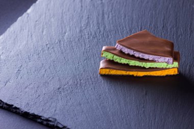 Siyah arka planda meyve doldurma ile çikolata. Yaban mersini, nane ve portakal ile çikolata dilimleri. Arduvaz tahta üzerinde koyu çikolata