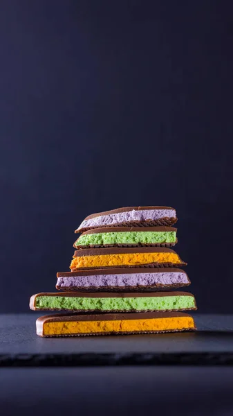 Chocolate with fruit filling on black background. Slices of chocolate with blueberries, mint and orange. Dark chocolate on slate board