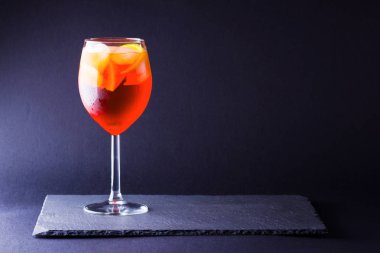 Koyu arka planda kokteyl Aperol Spritz. Minimalizm tarzında turuncu meyve ile yaz alkol kokteyli. İtalyan kokteyl Aperol Spritz arduvaz kurulu