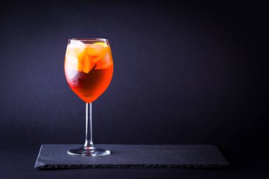 Koyu arka planda kokteyl Aperol Spritz. Minimalizm tarzında turuncu meyve ile yaz alkol kokteyli. İtalyan kokteyl Aperol Spritz arduvaz kurulu