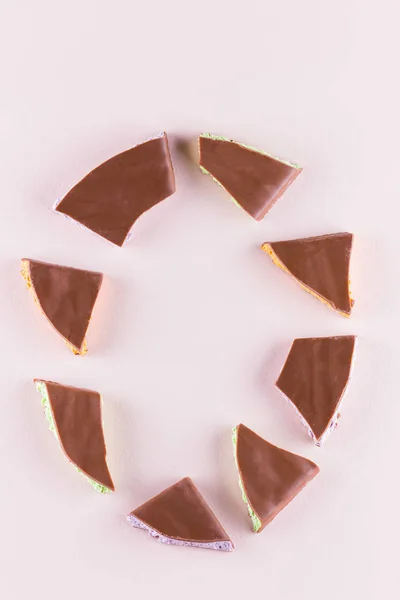 Chocolate with fruit filling on pink background. Slices of chocolate with blueberries, mint and orange. Dark chocolate on pastel color background