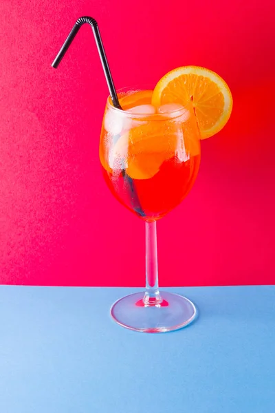 カクテル Aperol スプリッツ赤青の背景に オレンジ スライスと夏アルコール カクテル 色付きの背景に Aperol スプリッツ サンゴ色のミニマリズム — ストック写真