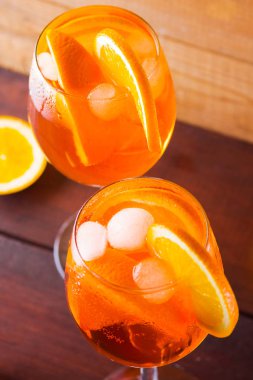 Kokteyl aperol spritz ahşap kurullarında. İki bardak portakal dilimleri ile yaz alkollü kokteyl ile. İtalyan kokteyl aperol spritz ve turuncu ahşap arka plan üzerinde çikolata parçalarını