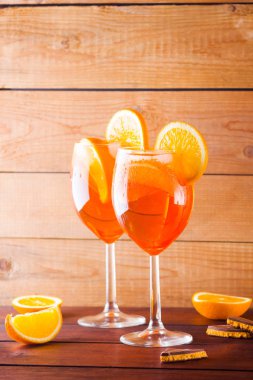 Kokteyl aperol spritz ahşap kurullarında. İki bardak portakal dilimleri ile yaz alkollü kokteyl ile. İtalyan kokteyl aperol spritz ve turuncu ahşap arka plan üzerinde çikolata parçalarını