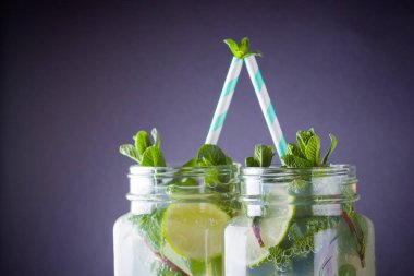 Mojito ve siyah arka plan üzerine nane. Kireç ve kayrak tahta üzerinde taze nane ile kokteyl serinletici. İki kulplu bir yaz içeceği ile narenciye ve buz ile kavanozları. El ile ahşap juicer ve mojito