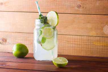 Mojito ve ahşap zemin üzerine nane. Kireç ve ahşap kurullarında taze nane ile kokteyl serinletici. İki kulplu bir yaz içeceği ile narenciye ve buz ile kavanozları. Ev yapımı mojito