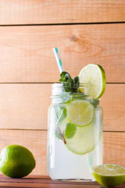 Mojito ve ahşap zemin üzerine nane. Kireç ve ahşap kurullarında taze nane ile kokteyl serinletici. İki kulplu bir yaz içeceği ile narenciye ve buz ile kavanozları. Ev yapımı mojito