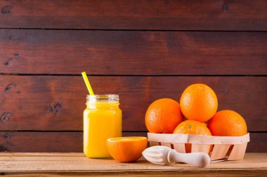 Ahşap tahta üzerinde turuncu meyve ve meyve suyu. Manuel juicer ile meyve suyu yapmak için Narenciye meyve. Ahşap kutuda Portakallar. Portakal suyu ile Mason kavanoz