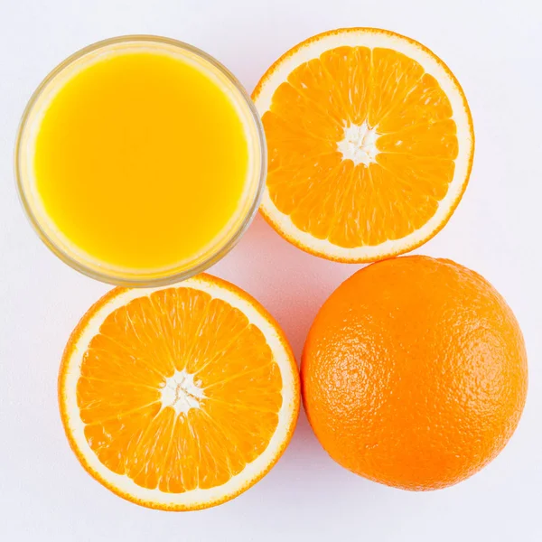 stock image Orange fruits with juice, concept. Orange juice and halves of oranges on white background. Citrus for making juice. Whole and squeezed oranges and glass of juice